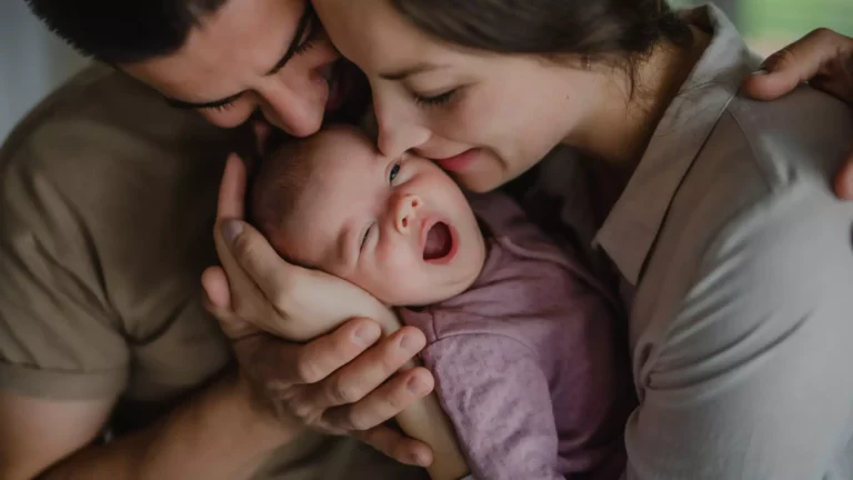 A mother and a father holding an infant between them. Both parents are kissing the baby.